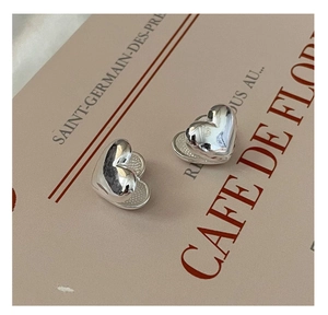 Detail of S925 sterling silver heart earrings with layered polished and textured finishes