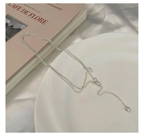 Detail of adjustable silver heart pendant with sliding toggle clasp on ceramic tray