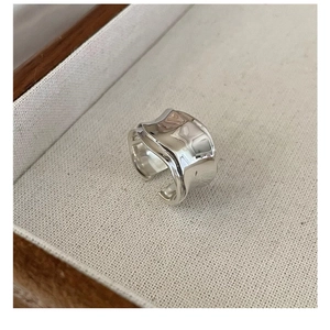 Macro shot of liquid metal style wavy silver ring on a beige jewelry display