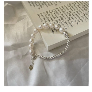 Gros plan d'un bracelet en perles d'argent S925 et perles d'eau douce avec pampille cœur