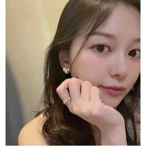 Close-up of minimalist silver heart studs and matching ring worn by a model