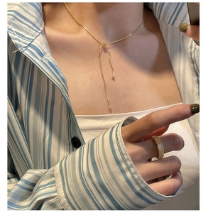 Detail of adjustable gold snake chain necklace and textured band ring on a model