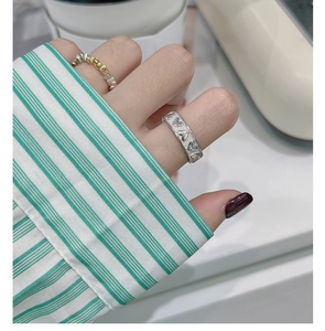 Detailed view of silver heart relief ring and twisted beaded band on finger