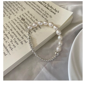 Détail d'un bracelet en argent S925 avec perles d'eau douce sur un livre et du satin