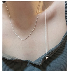 Detail of adjustable S925 sterling silver heart tassel choker necklace on a female model