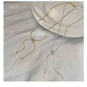 Detail of adjustable gold and silver snake bone necklaces on white silk background