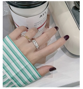 Detail of S925 silver cutout heart ring and bicolor heart-link band on finger