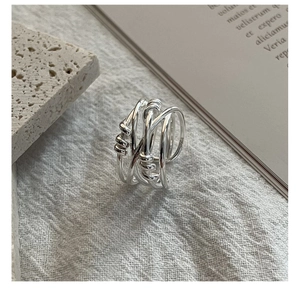 Macro shot of a multi-layer woven silver ring on textured linen and stone base