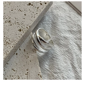 Close-up of S925 sterling silver multi-layer woven ring on a textured stone surface