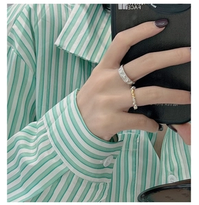 Close-up of a silver embossed ring and a mixed-metal textured ring set worn by a model