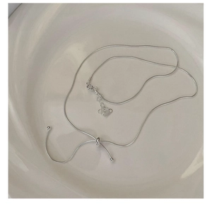 Detail of adjustable silver snake chain necklace with sliding bead on white plate