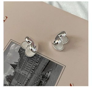 Detailed view of silver heart-shaped stud earrings with textured crumpled metal finish