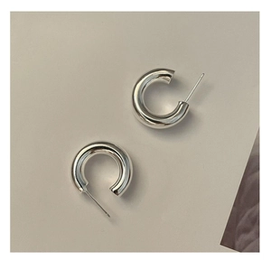Macro shot of silver C-shaped chunky hoop earrings with a mirror polished finish