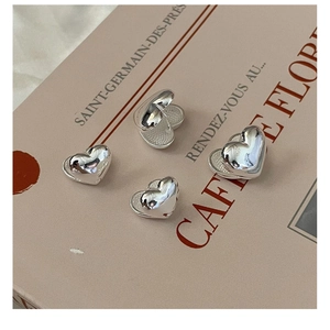 Detailed close-up of heart-shaped silver earrings on a vintage French book