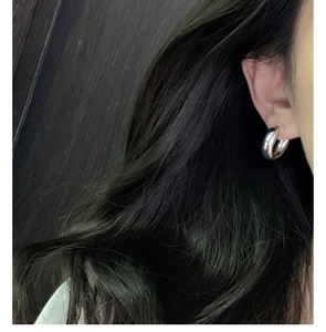 Close-up of polished S925 sterling silver chunky C-shaped hoop earrings on model
