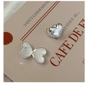 Detailed macro view of heart-shaped silver locket with interior honeycomb texture on a book