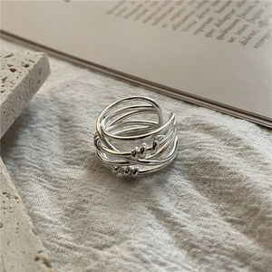 Elegant multi-layer woven S925 sterling silver ring displayed on textured fabric