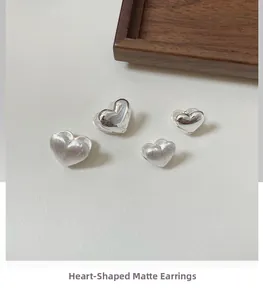 Detail of S925 silver heart earrings showing matte and polished finish textures