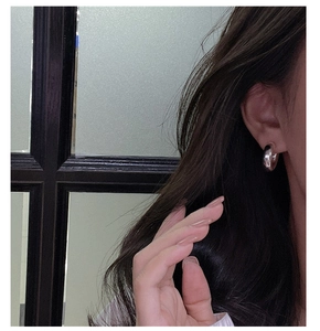 Close-up of minimalist S925 sterling silver C-shaped hoop earring with mirror finish on ear