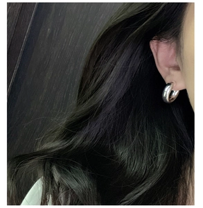 Close-up of minimalist S925 sterling silver thick C-shaped hoop earring on model ear