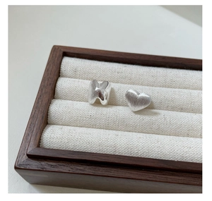 Macro view of S925 sterling silver heart and ribbon earrings with brushed matte finish
