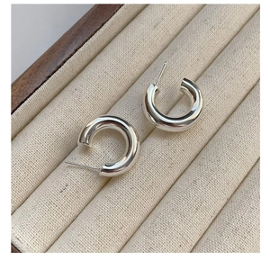 Detailed close-up of polished S925 sterling silver C-shaped hoop earrings in jewelry box
