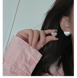 Close-up of silver heart-shaped earring on ear with brushed and polished finish