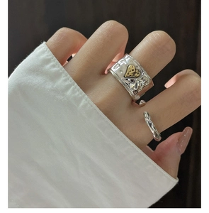 Macro detail of textured silver wide ring with gold heart and thin twisted band