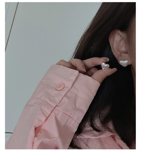 Close-up of minimalist S925 sterling silver heart earrings worn by a model in daily life