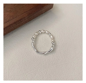 Dettaglio anello in argento S925 con metallo a onde irregolari e perle bianche
