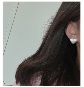Close-up of minimalist S925 sterling silver heart earrings with brushed texture on ear