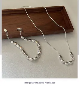 Nahaufnahme der S925 Sterling Silber Bohnen-Halskette und Schlangenkette auf Holztablett