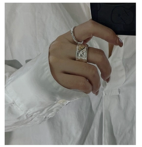 Detailed view of vintage wide-surface silver heart ring and twisted band on a hand