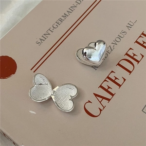 Polished S925 sterling silver heart locket earrings displayed on vintage French paper