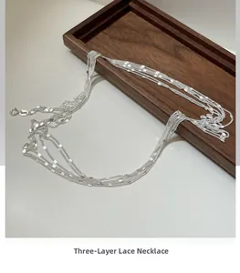 Close-up of a S925 sterling silver triple-layered lace chain necklace on a wood tray