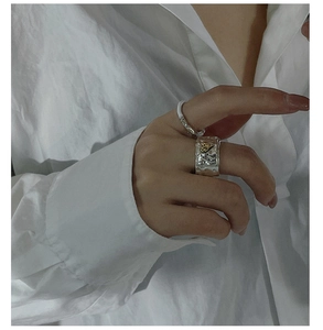 Detailed view of wide textured silver ring with gold heart on white shirt background