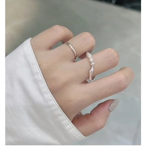 Dettaglio ravvicinato di anelli in argento sterling S925 con perle e design fluido