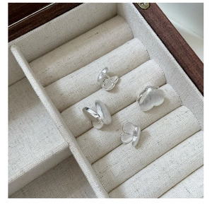 Close-up of heart and butterfly 925 silver earrings with matte brushed texture finish