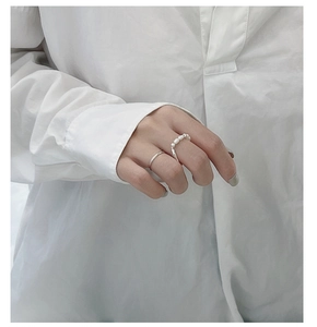 Dettaglio del set di anelli in argento S925 con perla bianca sulla mano della modella