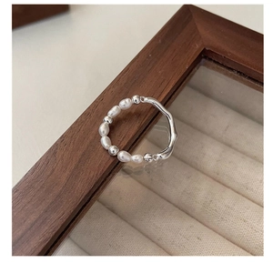 Dettaglio dell'anello irregolare in argento S925 con perle bianche su vassoio elegante