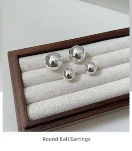 Detailed view of polished S925 silver ball earrings in two sizes on display stand