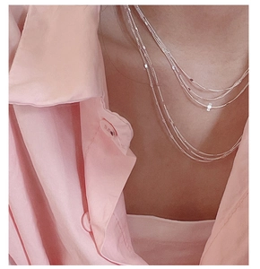 Close-up of layered S925 sterling silver lace chain necklace worn with a pink shirt