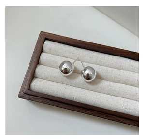 Detail of high-polished S925 sterling silver ball stud earrings on a wooden tray