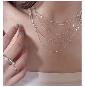 Detail of layered S925 silver lace chain necklace and pearl ring on female model