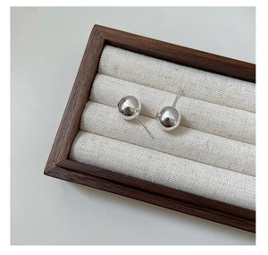 Detailed view of polished S925 sterling silver ball stud earrings on a jewelry display tray