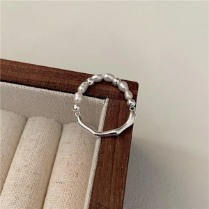 Anello con perle barocche e fascia irregolare in argento liquido su portagioie in legno