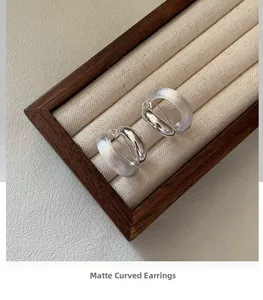 Macro detail of 925 sterling silver curved earrings with matte and polished finish textures