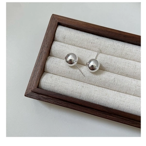 Macro detail of polished S925 sterling silver ball stud earrings on a linen jewelry display