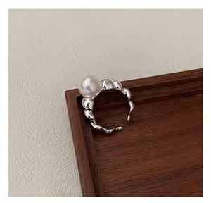 Close-up of S925 silver croissant ring with large white pearl on textured background