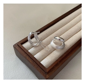 Macro detail of brushed silver C-hoop earrings featuring a polished mirror-like interior